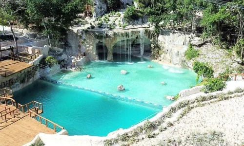 Scenic view of a turquoise lagoon with waterfalls, surrounded by lush greenery in Punta Cana, ideal for family activities.