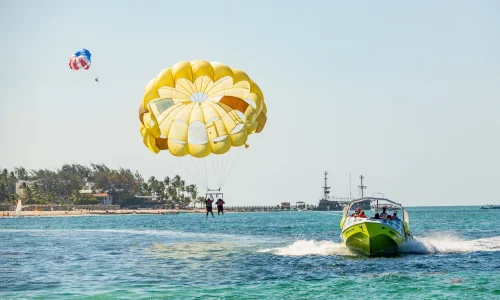 Parasailing over Punta Cana beach with a speedboat, showcasing water activities and scenic coastal views.