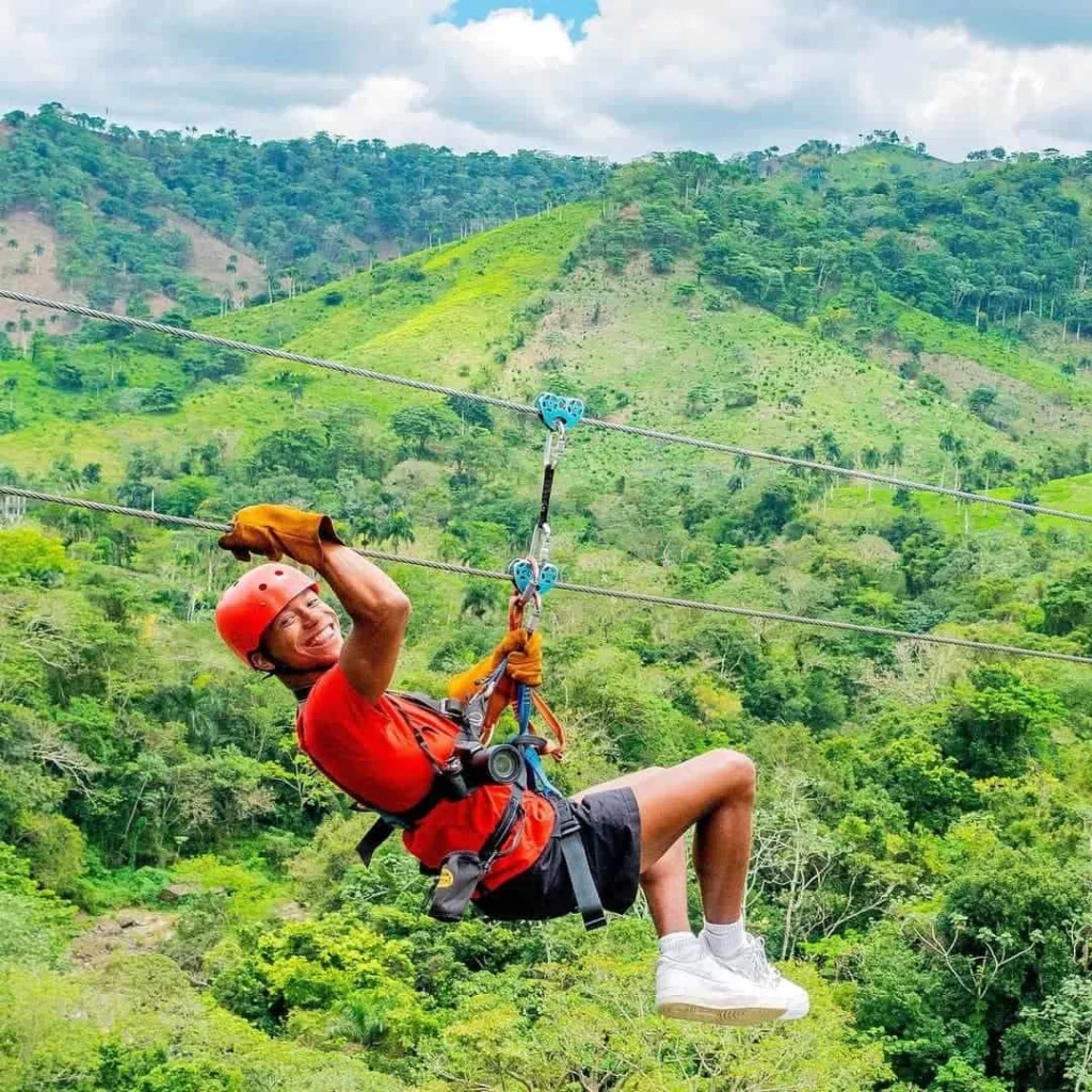 Man zip-lining through lush greenery in Punta Cana, enjoying an adventurous outdoor activity.