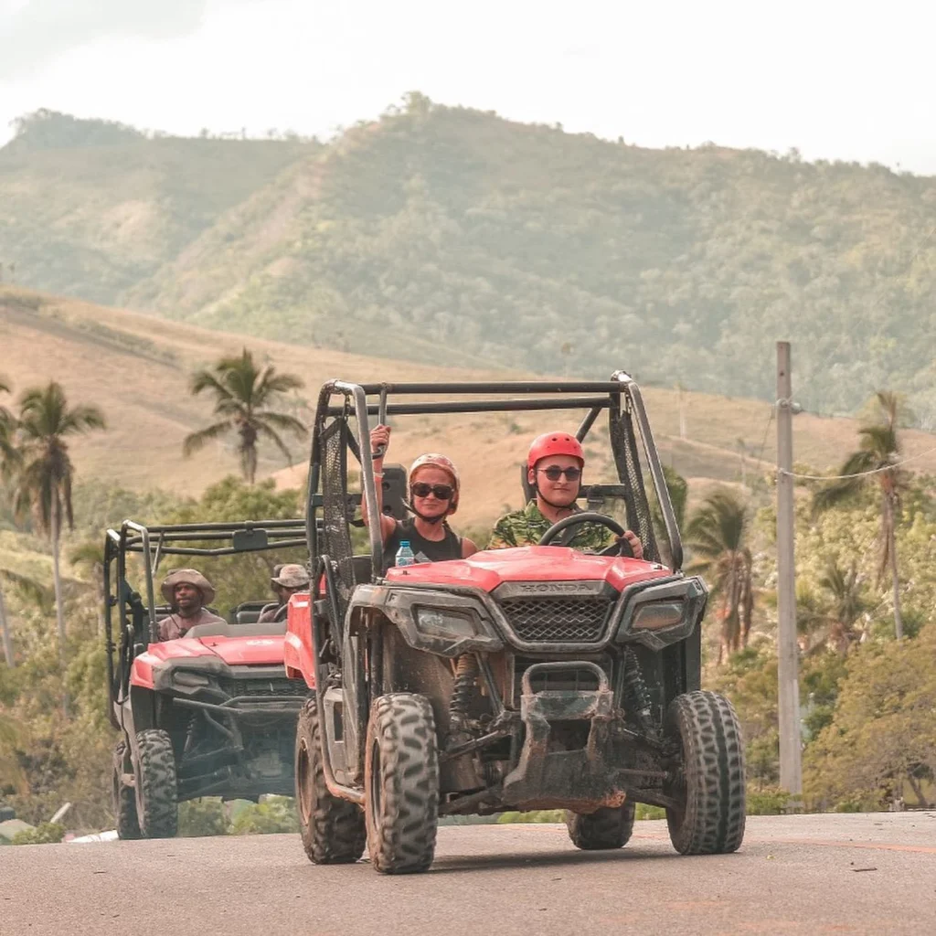 Excited tourists driving ATVs through scenic Punta Cana hills, ready for adventure and exploration.