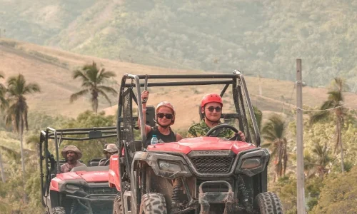 Excited tourists driving ATVs through scenic Punta Cana hills, ready for adventure and exploration.