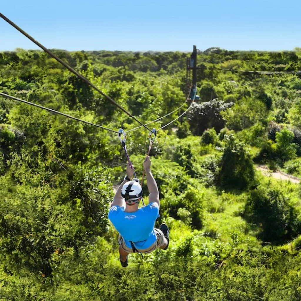 A person zip-lining over lush greenery in Punta Cana, showcasing adventure activities in a tropical setting.