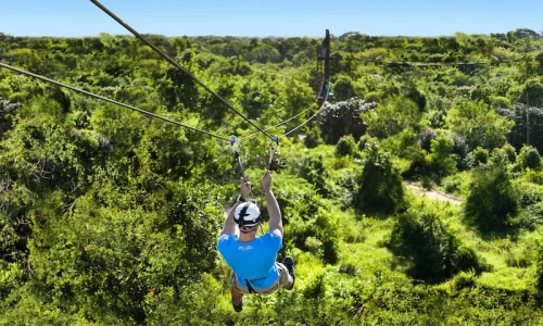 A person zip-lining over lush greenery in Punta Cana, showcasing adventure activities in a tropical setting.